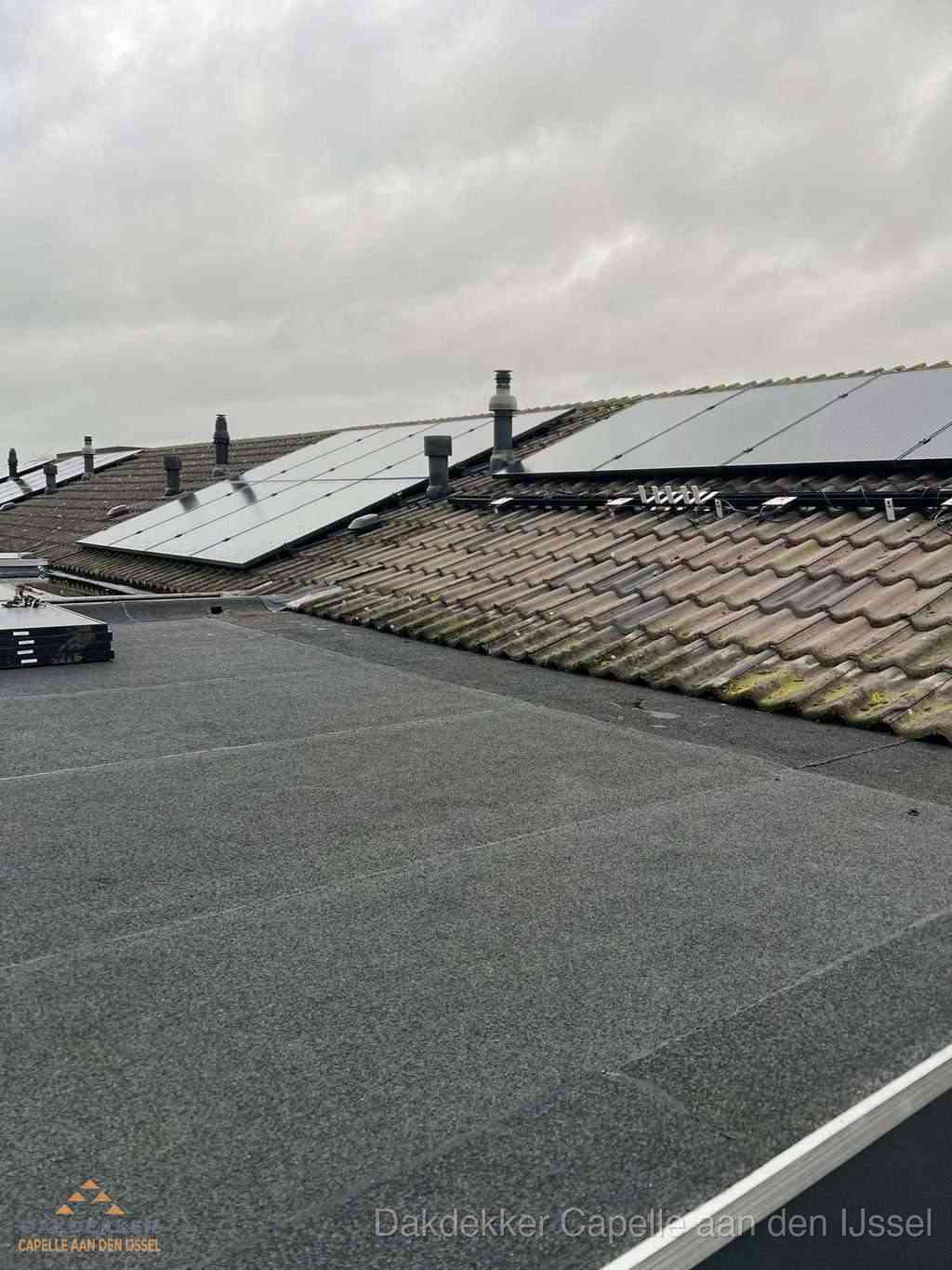Plat dak inspectie met bitumen bedekking naast schuin pannendak in Capelle aan den IJssel