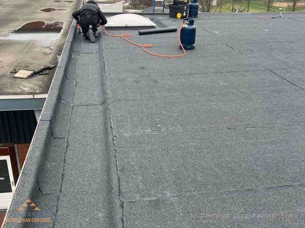 Dakdekker repareert bitumen dakbedekking op groot plat dak in Capelle aan den IJssel